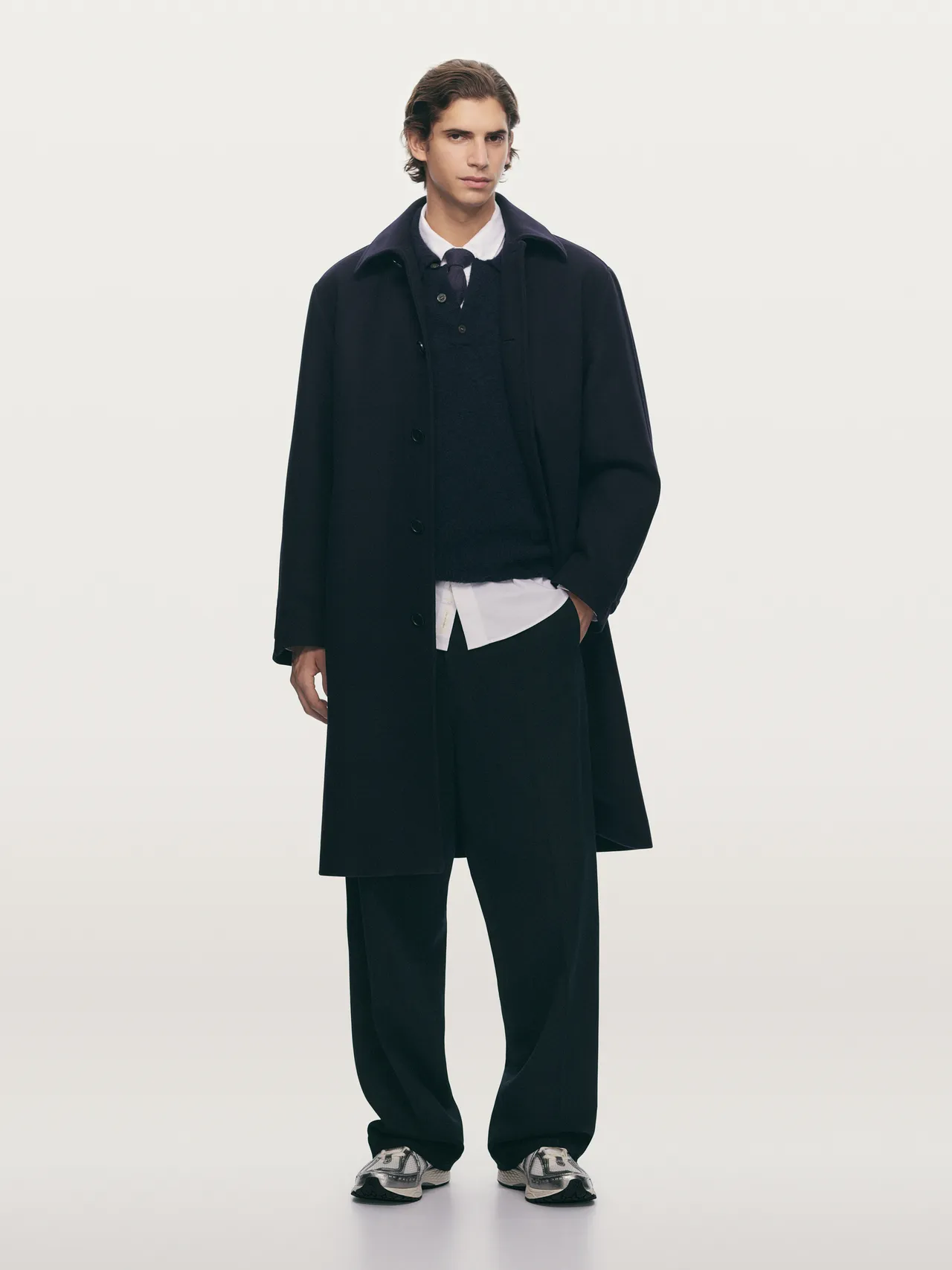 Model in a navy overcoat layered with knitwear.
