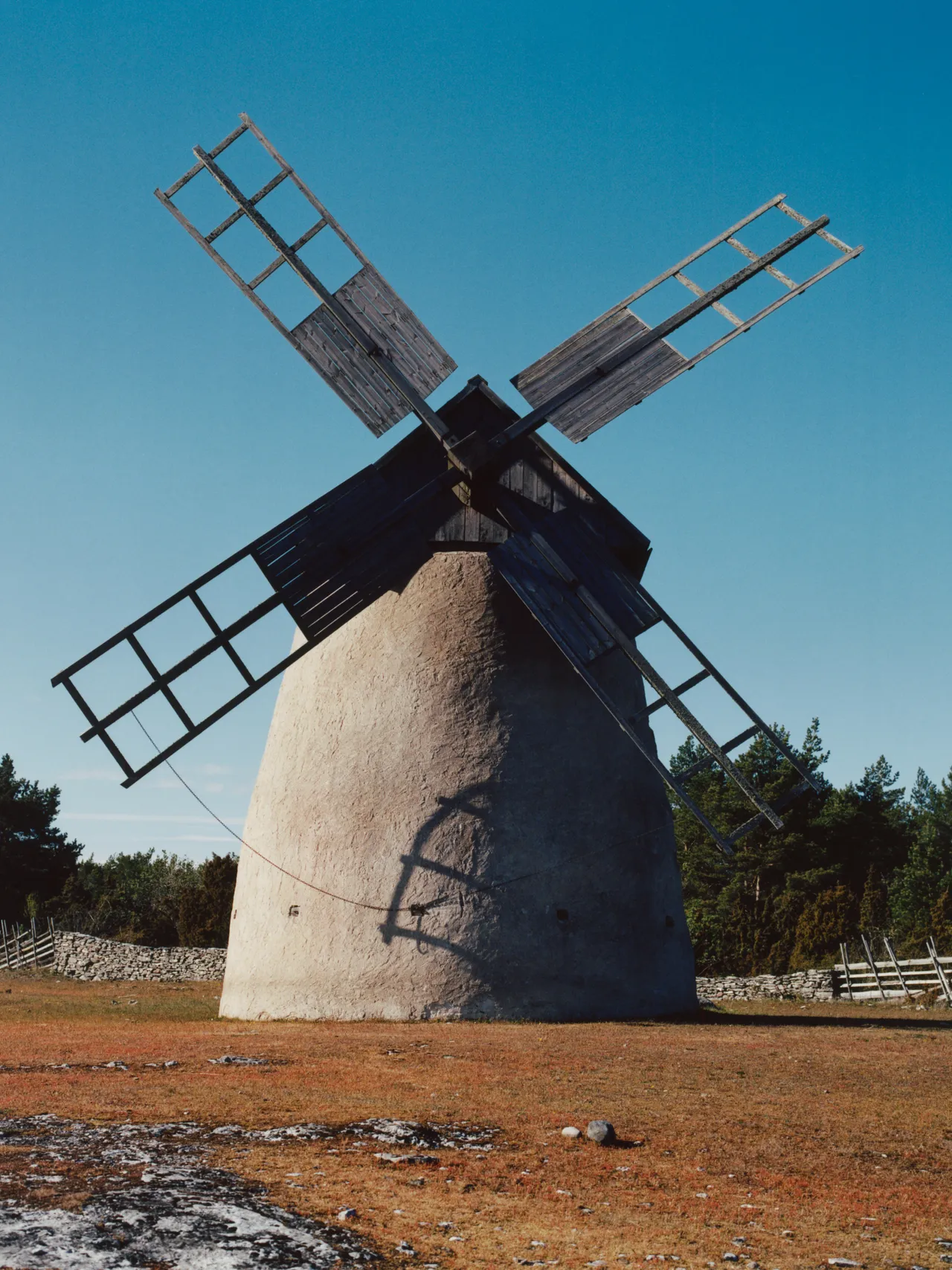 Windmill standing in a rural landscape under a blue sky.