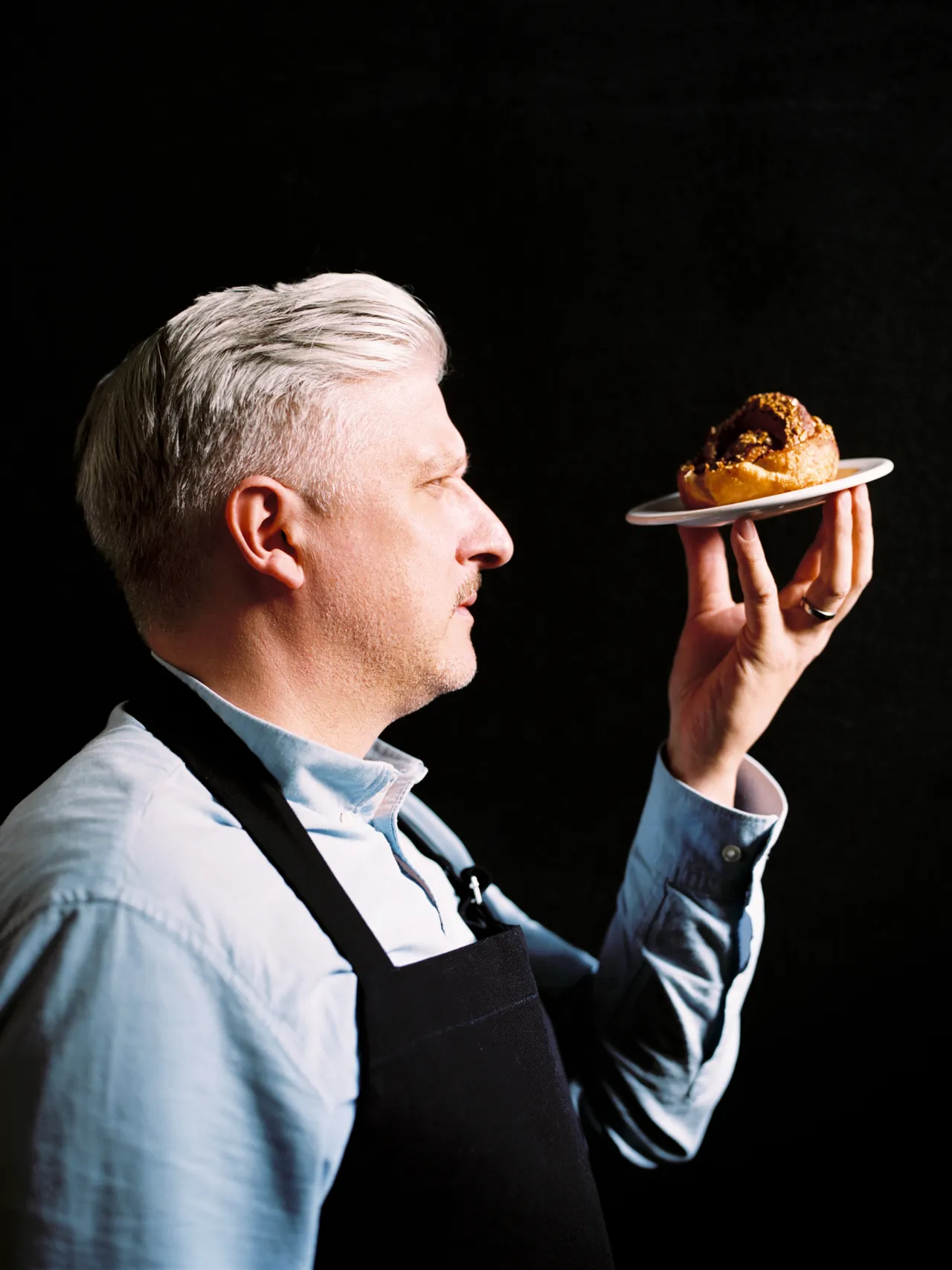 Chef presenting a cinnamon bun on a small plate.